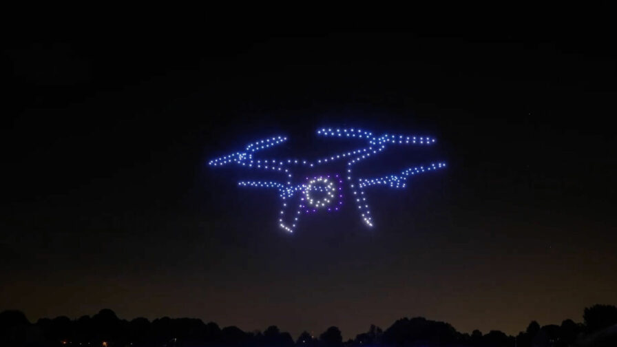 Mehrere synchronisierte Drohnen formen eine Lichtinstallation am Nachthimmel.