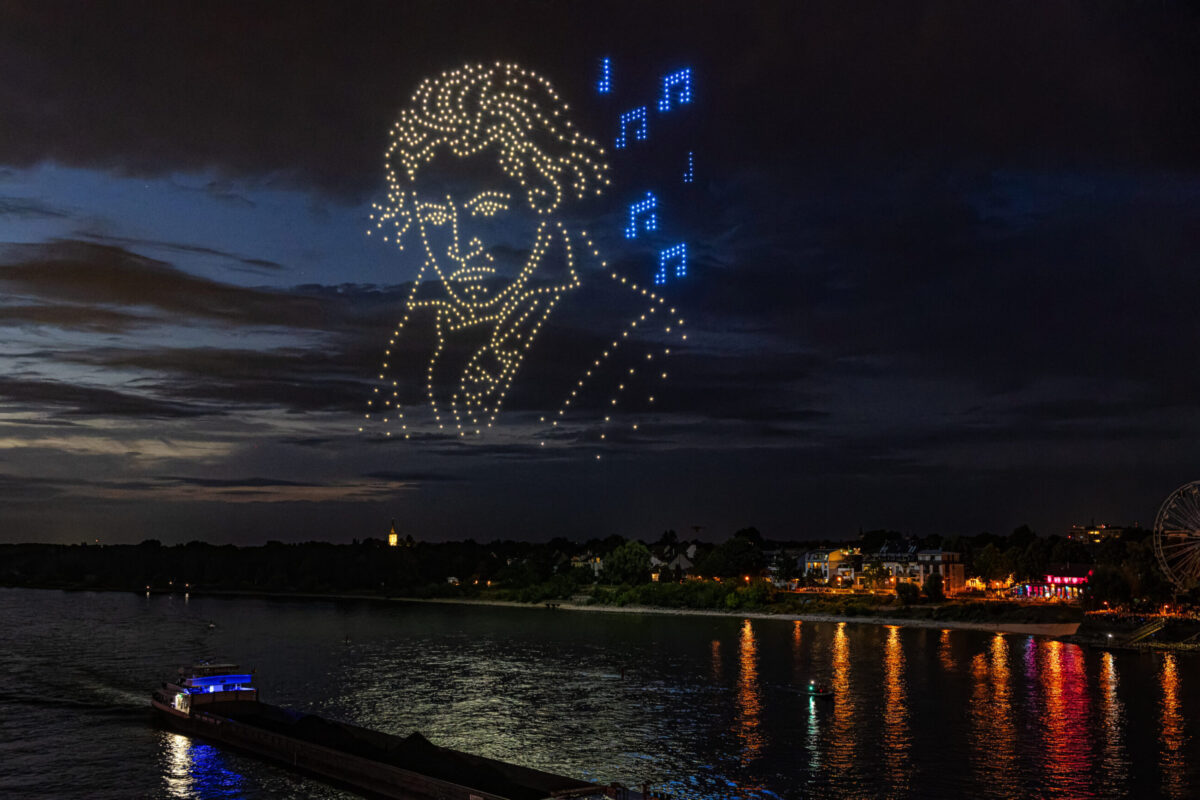 Großflächige Lichtinszenierung durch Drohnen bei Nacht.