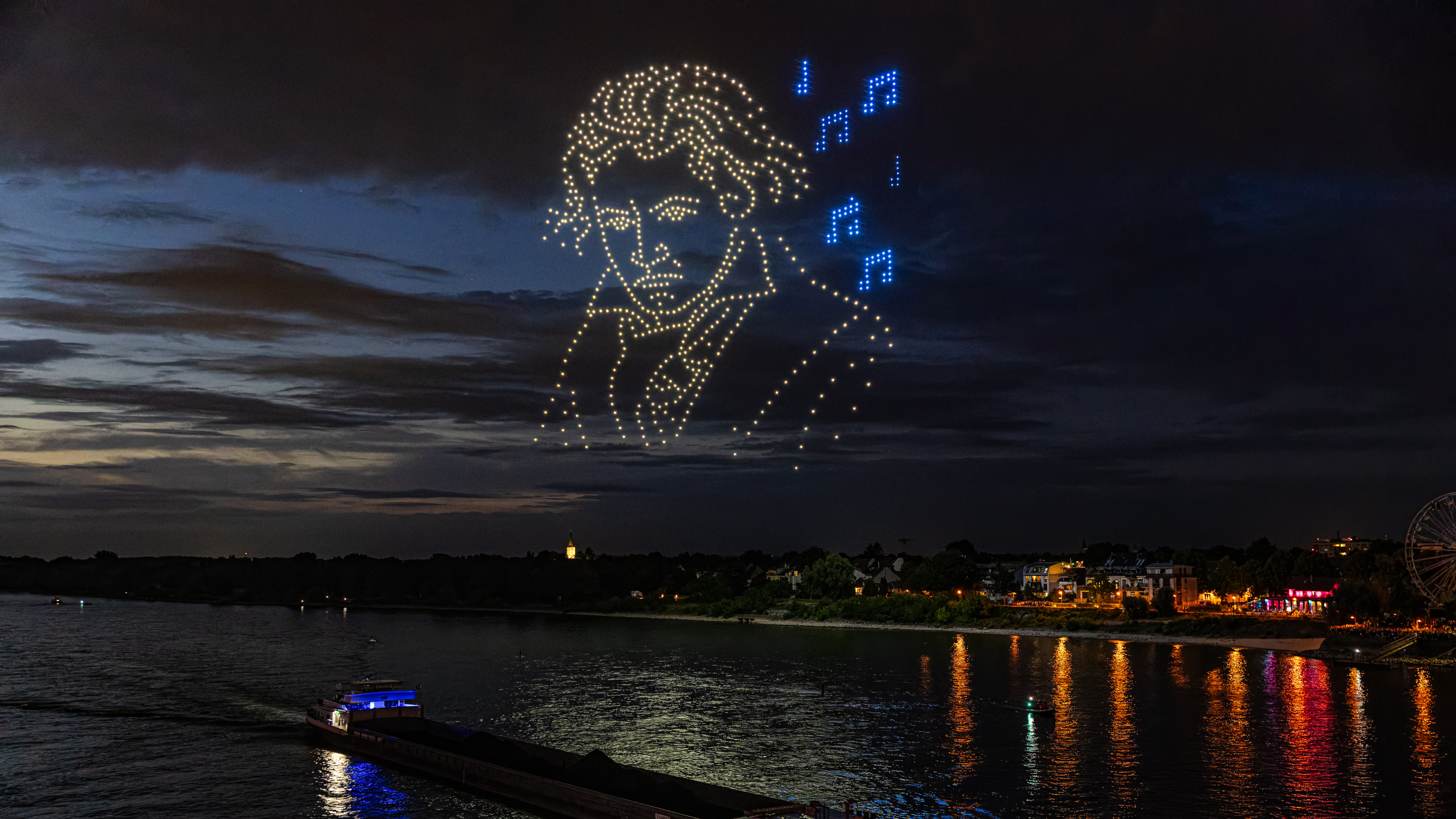 Großflächige Lichtinszenierung durch Drohnen bei Nacht.