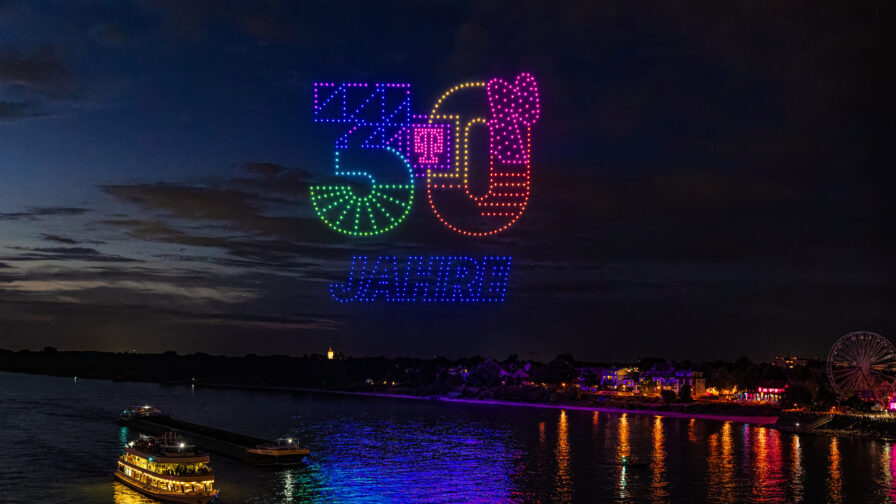 Mehrere hundert synchronisierte Drohnen als Lichtinstallation am Nachthimmel.