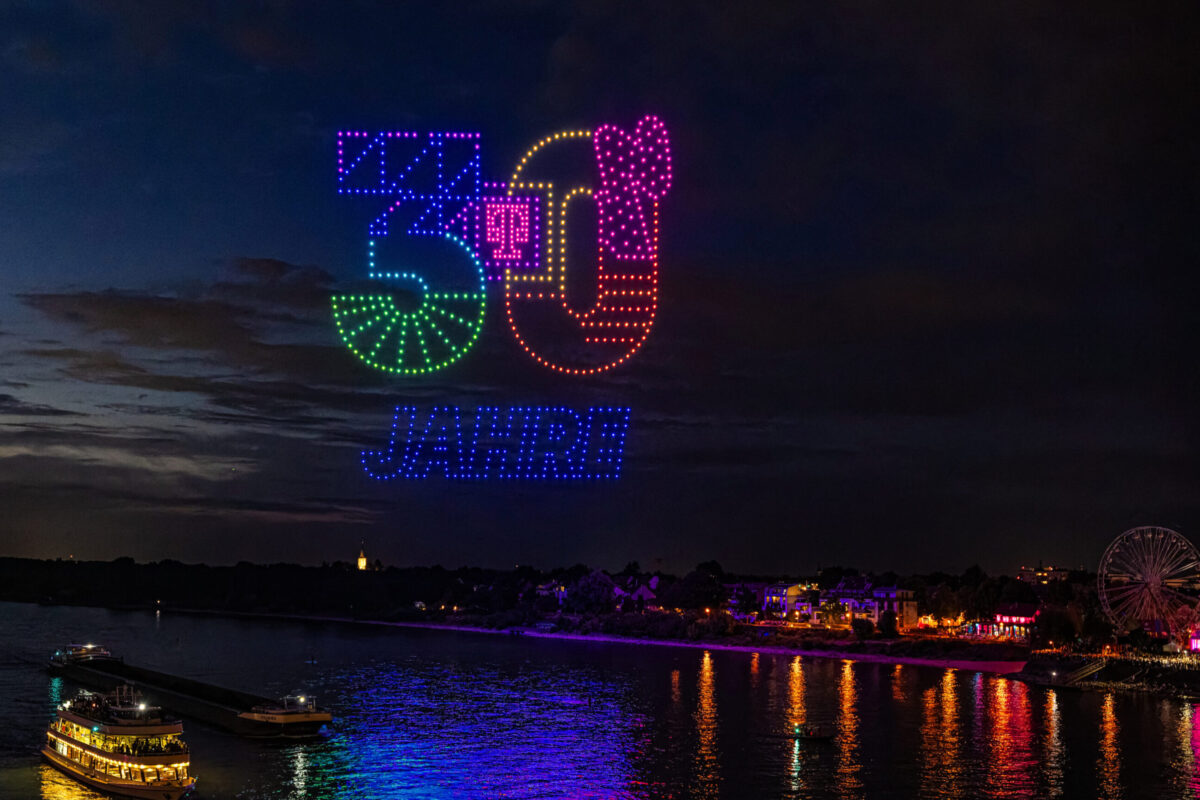 Mehrere hundert synchronisierte Drohnen als Lichtinstallation am Nachthimmel.