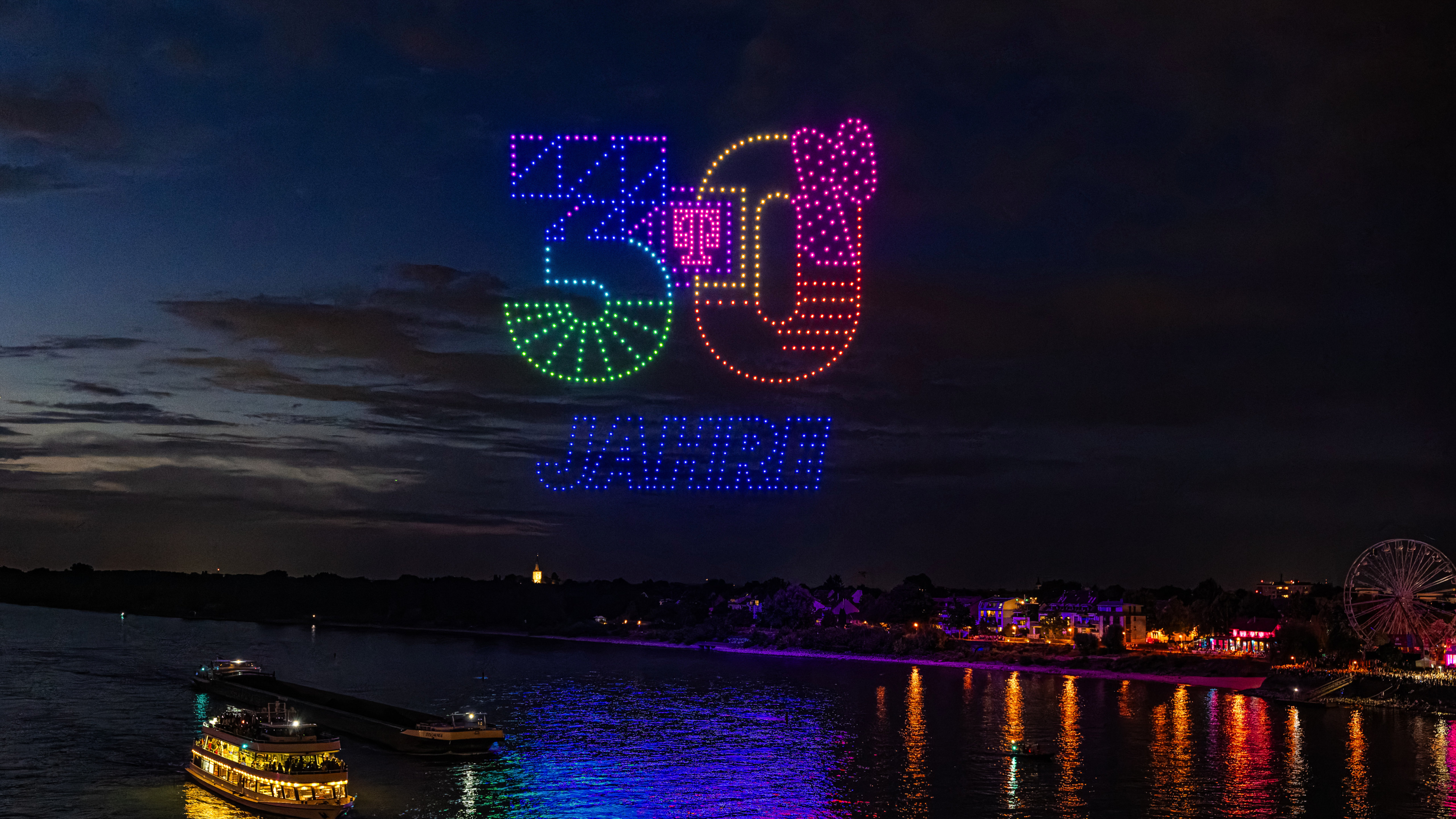Mehrere hundert synchronisierte Drohnen als Lichtinstallation am Nachthimmel.