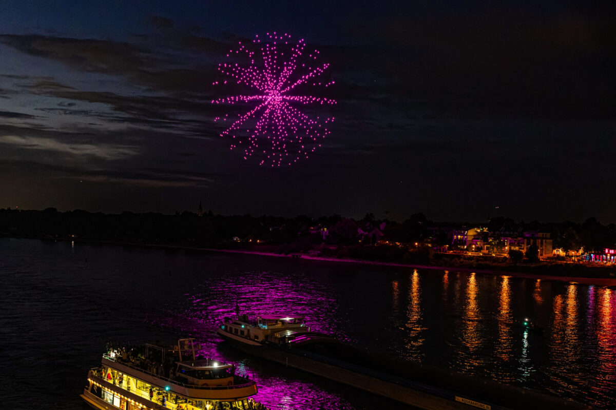 Großformatige Drohnenshow über einer Stadt mit synchronisierten Lichtformationen.