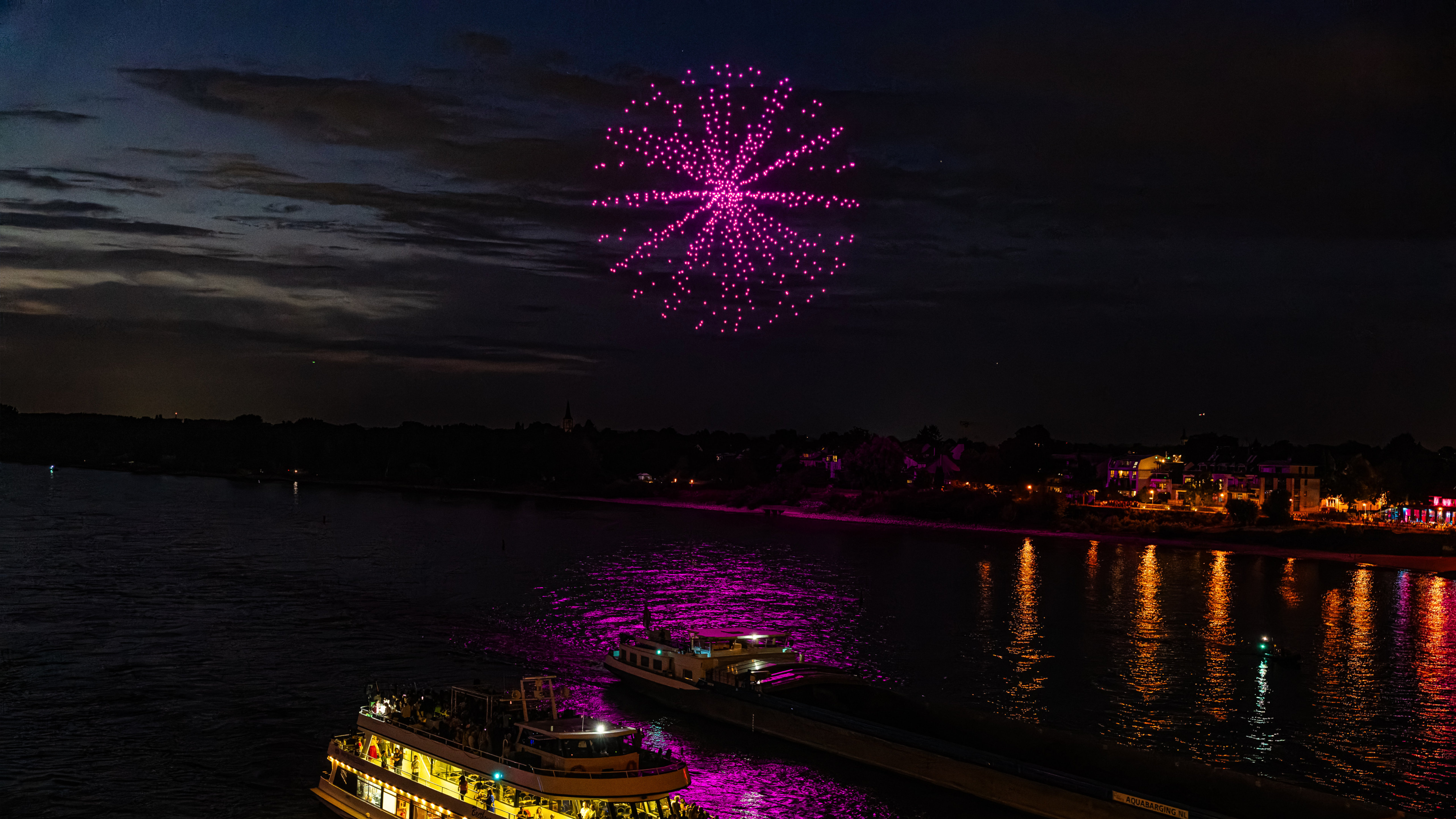 Großformatige Drohnenshow über einer Stadt mit synchronisierten Lichtformationen.
