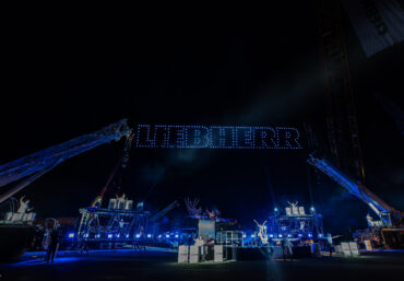 Drohnenshow bei einem Corporate Event mit synchronisierten Lichtformationen am Nachthimmel.
