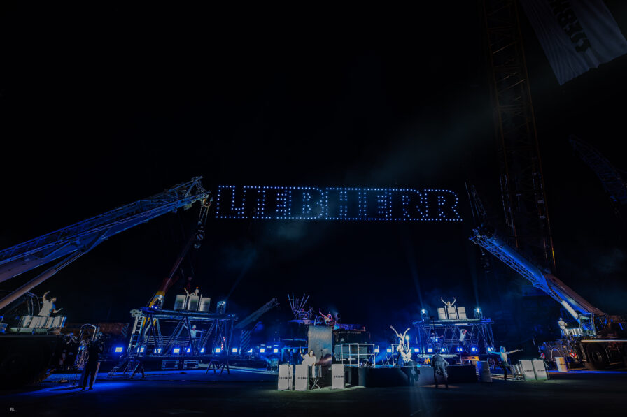Drohnenshow bei einem Corporate Event mit synchronisierten Lichtformationen am Nachthimmel.