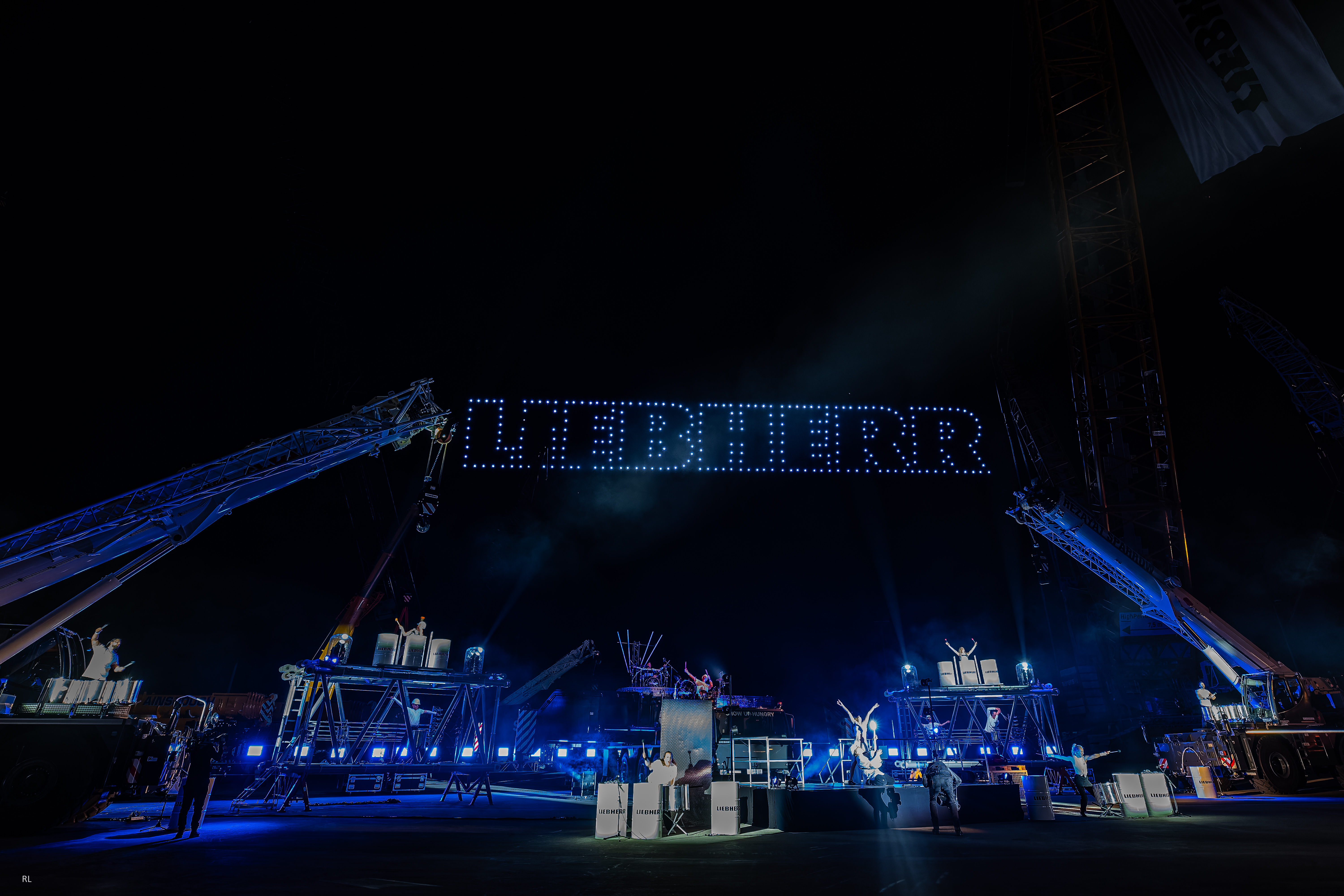 Drohnenshow bei einem Corporate Event mit synchronisierten Lichtformationen am Nachthimmel.