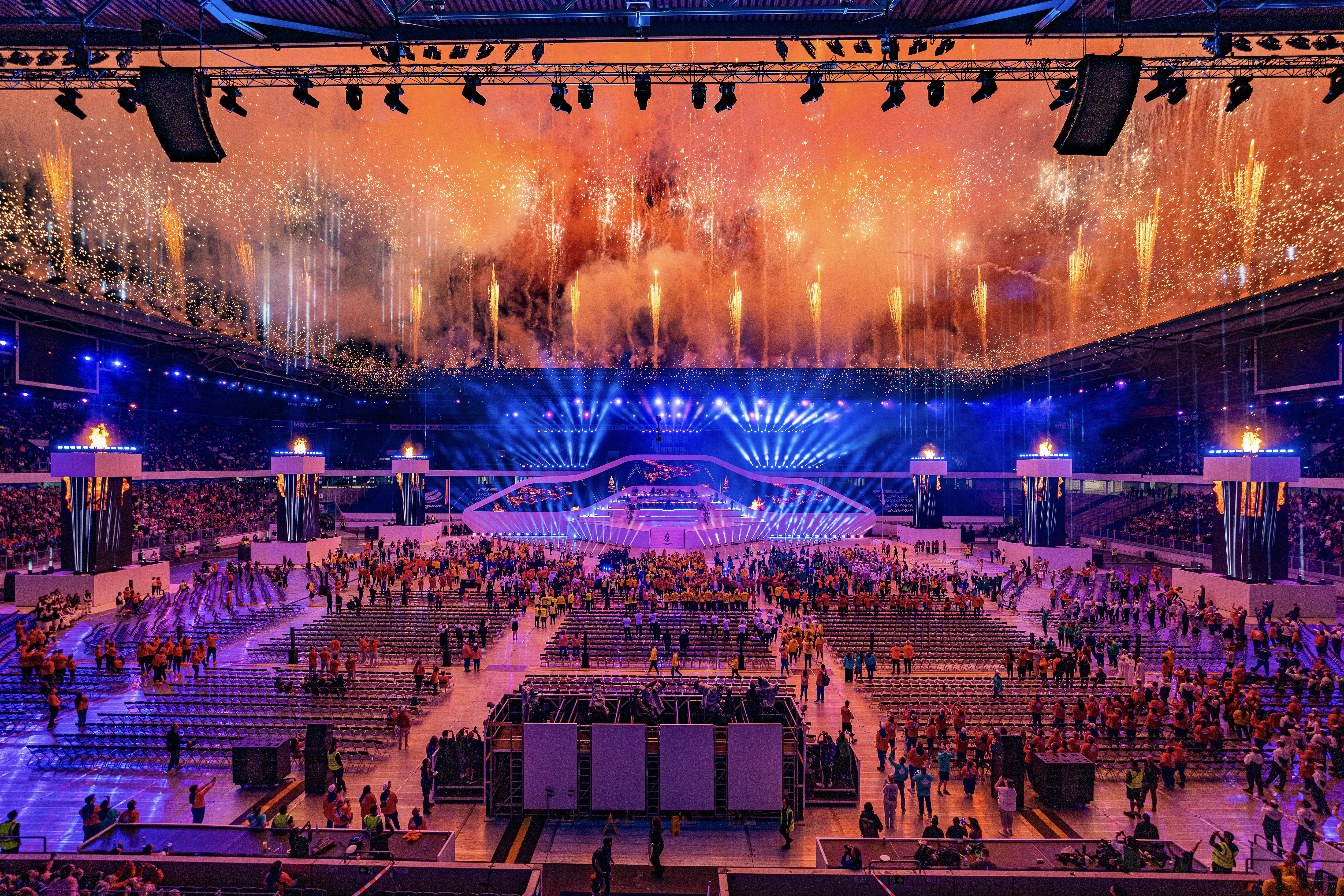 Panoramaaufnahme von Feuerwerksformationen mit mehrstufigen Höhenbildern über dem Stadion.