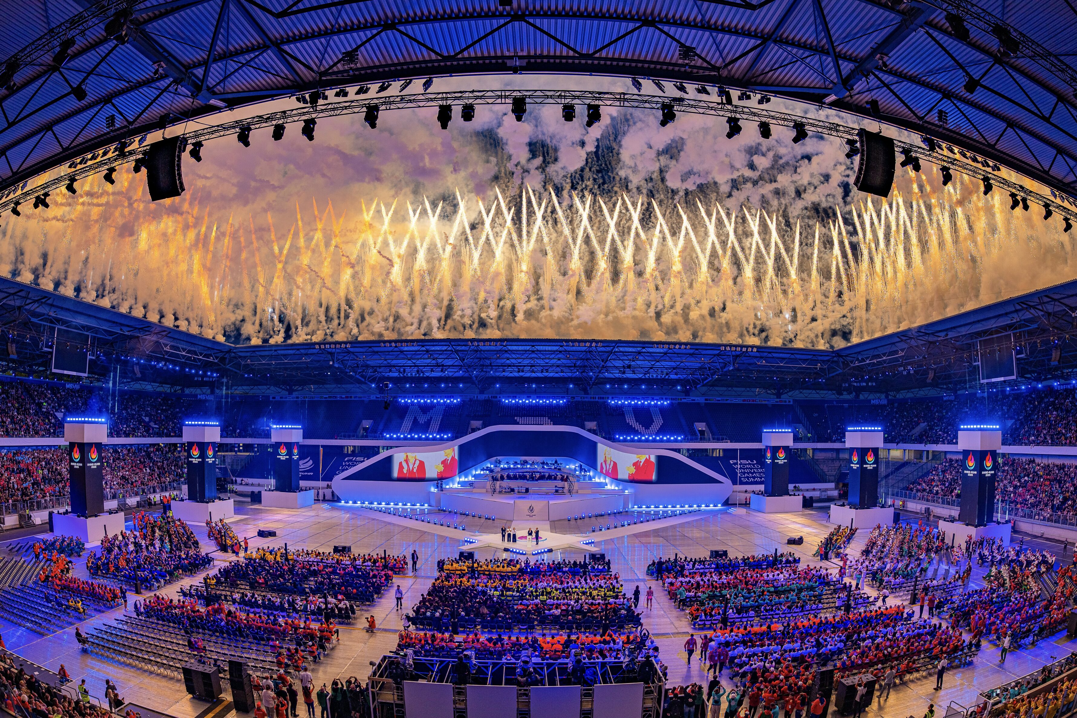 Synchron gezündete Boden- und Höhenpyrotechnik mit klaren Linien und symmetrischer Anordnung bei einer Lunatx Pyroshow im Stadion.