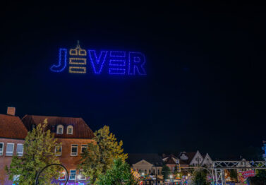 Stadtlogo Jever als leuchtende Drohnenformation am Nachthimmel