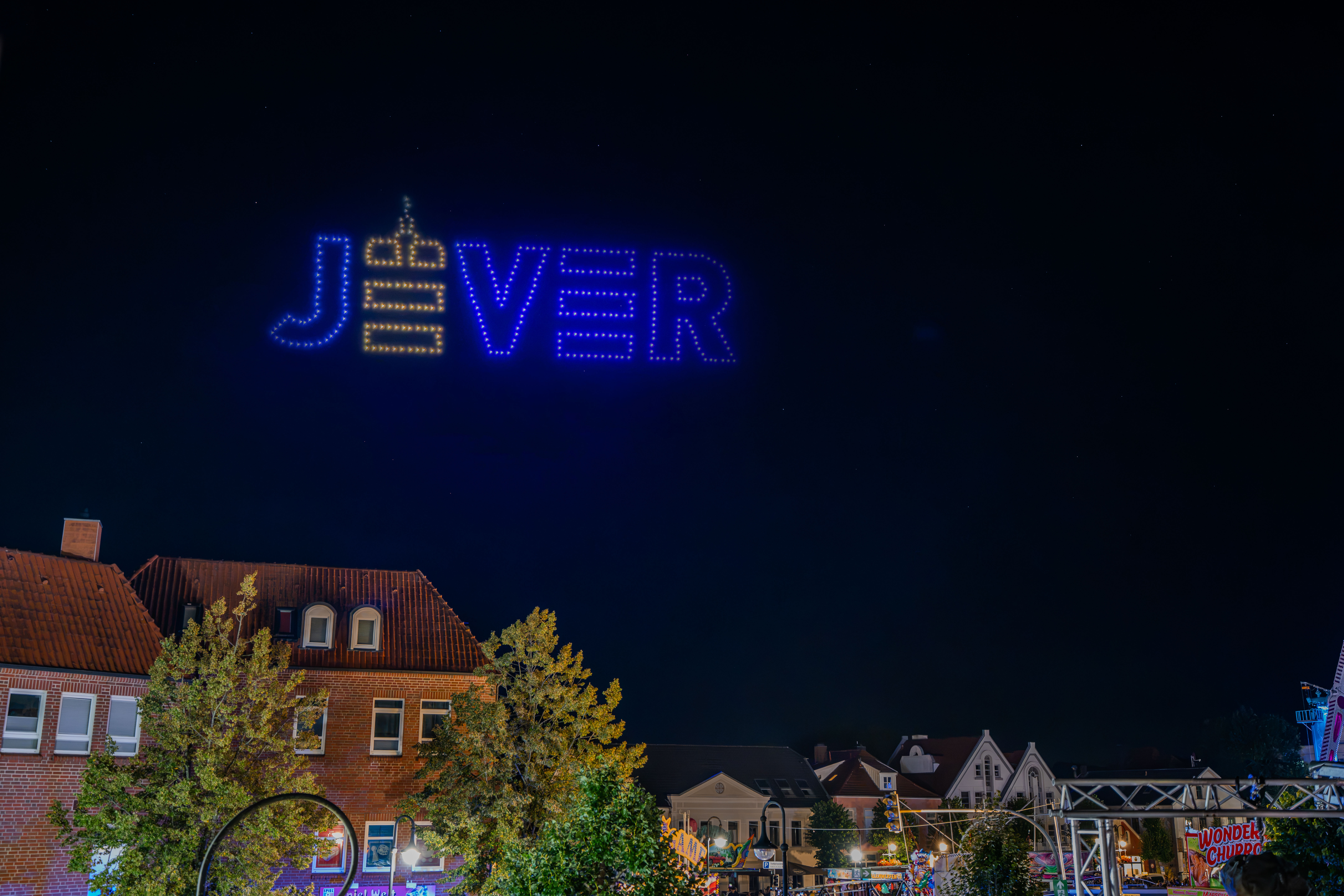 Stadtlogo Jever als leuchtende Drohnenformation am Nachthimmel